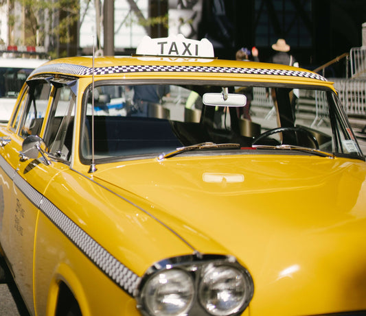 Yellow Checker Taxi Cab parked on a busy city street